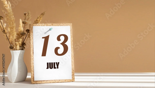 Fototapeta july 13. 13th day of month, calendar date.White vase with dead wood next to cork board with numbers. White-beige background with striped shadow. Concept of day of year, time planner, summer month