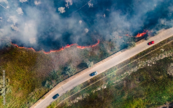 Fototapeta Top view at the beginning of the fire in a grassy field near the road