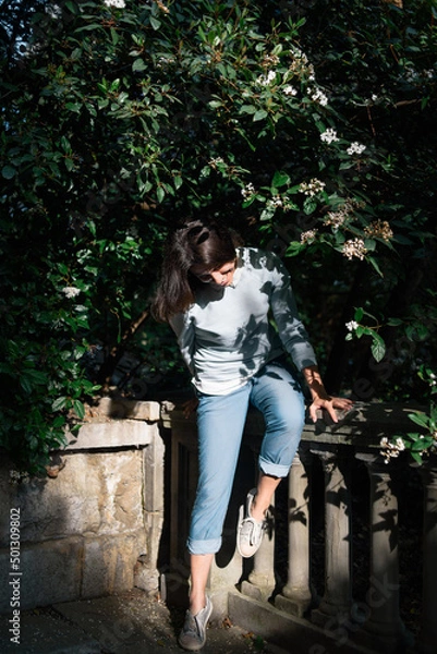 Obraz Happy smiling brunette woman hide in shadows of blossoming branch.