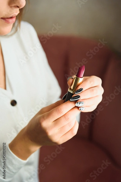 Obraz Hands with manicure hold red luxury lipstick