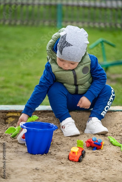 Fototapeta portrait of a 2 year old boy. Played in the playground in the sand on the street.