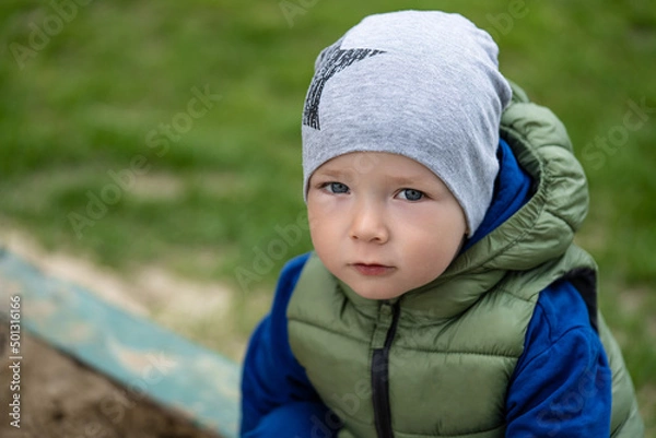 Fototapeta portrait of a 2 year old boy. Played in the playground in the sand on the street.