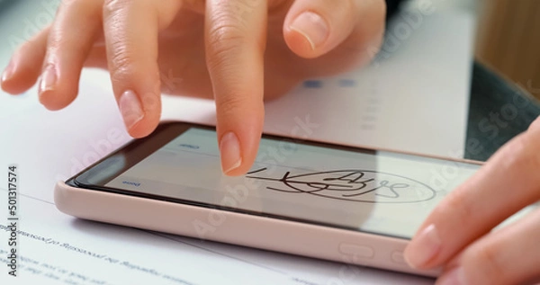 Fototapeta Electronic Signature on smartphone screen with woman hand. Sign Document of Deal at Work in Office Indoors. Write Business Agreement for Entrepreneur. Contract digital signature.