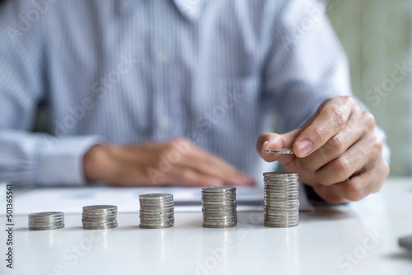Fototapeta Businessman with a coin in a piggy bank along with pressing the calculator and writing down savings for the future after retirement, ideas for saving money for the future and life after retirement