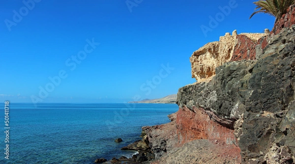 Fototapeta View along the cliff at Costa Calma on the island of Furteventura in the Canary Islands with a blue, cloudless sky and clear water