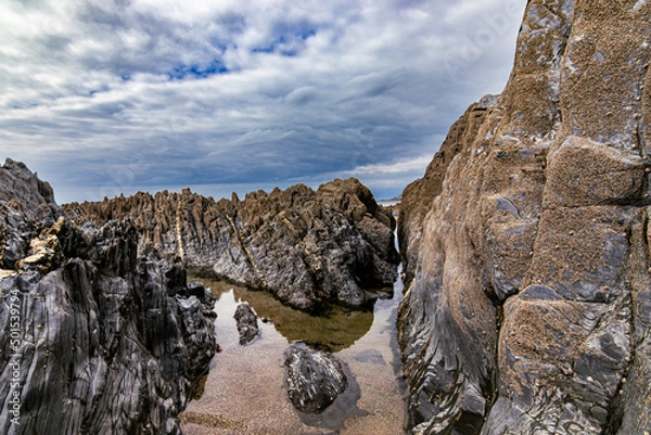 Obraz A beautiful clear rock pool, surrounded by dramatic rocks, with a stormy sky.  Mortehoe, near Woolacombe in North Devon.