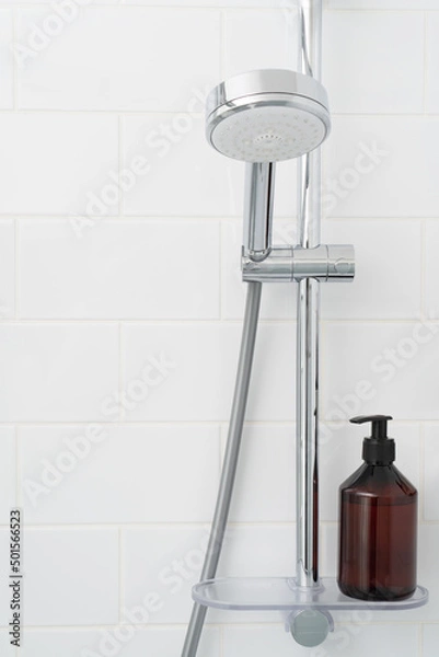 Fototapeta Shower rack with hanging shower head and shelf with bottle of gel.