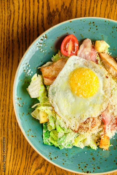 Obraz Caesar salad with large fried eggs
