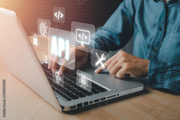 Fototapeta API - Application Programming Interface, Woman using laptop computer with VR screen API icon on office desk, Software development tool, modern technology, internet and networking concept..