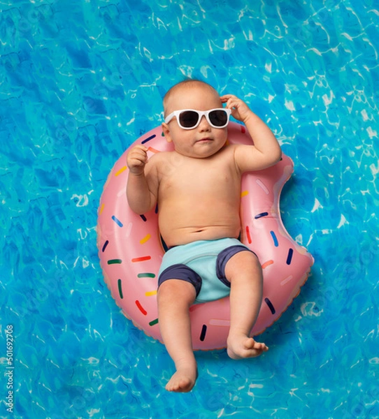 Fototapeta small child swims in the pool on an inflatable ring