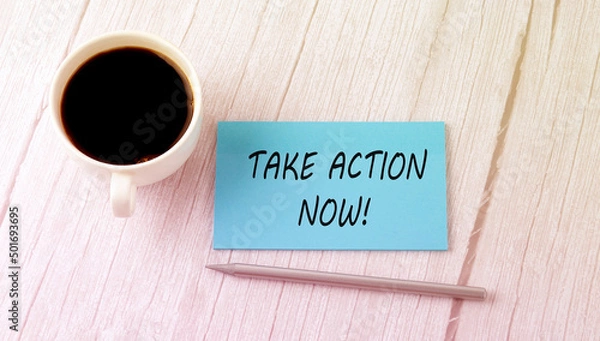 Fototapeta Take action Now text on the blue sticker with cofee and pen