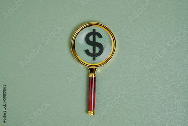 Fototapeta Dollar symbol under a magnifying glass, on a green background.