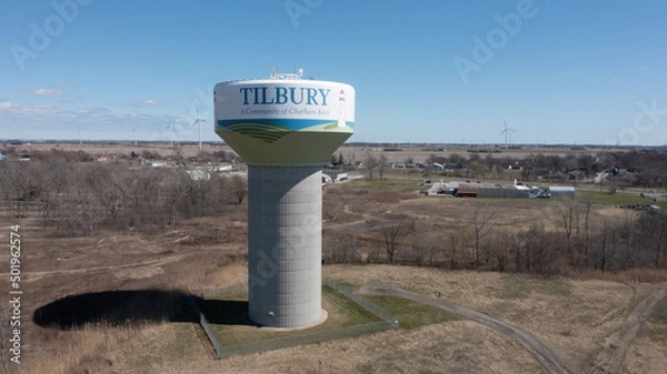 Fototapeta Aerial view of Tilbury water tower in the town of Tilbury, Ontario with wind turbines in the background.