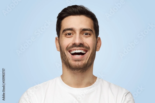 Fototapeta Attractive handsome unshaven young man in white t-shirt laughs out loud