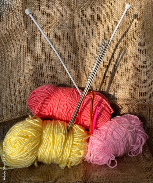 Obraz Multi-colored threads and knitting needles. Hobby knitting woolen threads. Threads on a brown background.