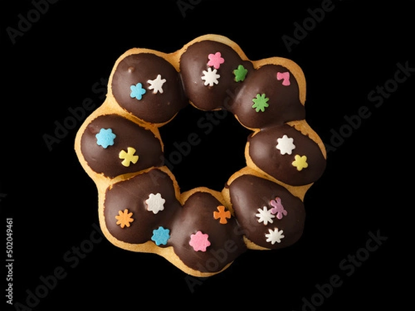 Fototapeta Cookies in the form of a ring in glaze and confetti on a black background.