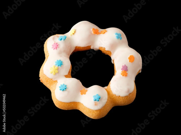 Fototapeta Cookies in the form of a ring in glaze and confetti on a black background.