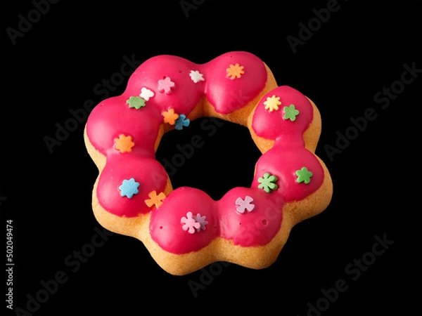 Fototapeta Cookies in the form of a ring in glaze and confetti on a black background.