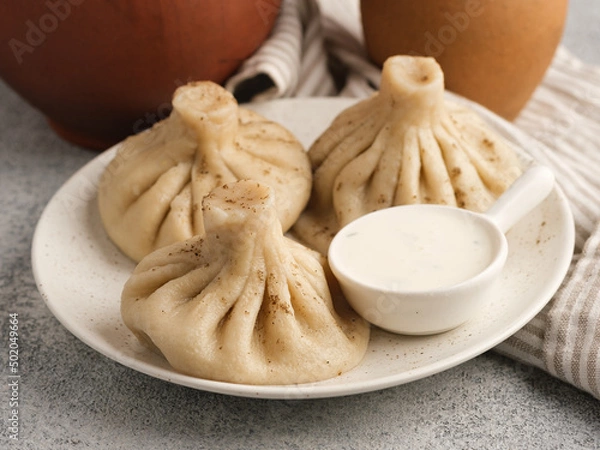 Fototapeta Khinkali in a white plate with sauce.
