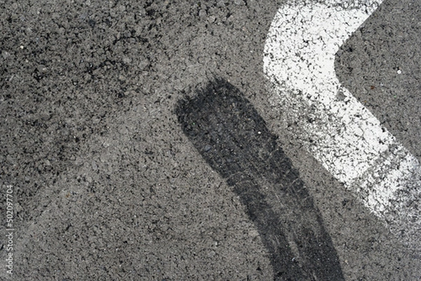 Fototapeta Asphalt texture with white line and tire marks. Smooth asphalt road. Tarmac dark grey grainy road background.Top view