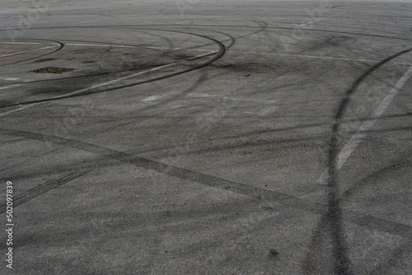 Fototapeta Asphalt texture with white line and tire marks. Smooth asphalt road. Tarmac dark grey grainy road background.Top view