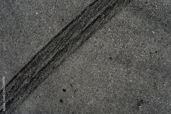 Fototapeta Asphalt texture with white line and tire marks. Smooth asphalt road. Tarmac dark grey grainy road background.Top view