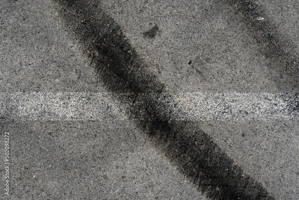 Fototapeta Asphalt texture with white line and tire marks. Smooth asphalt road. Tarmac dark grey grainy road background.Top view
