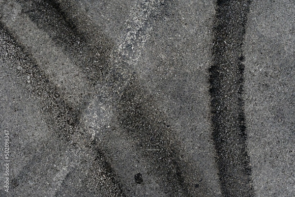 Fototapeta Asphalt texture with white line and tire marks. Smooth asphalt road. Tarmac dark grey grainy road background.Top view