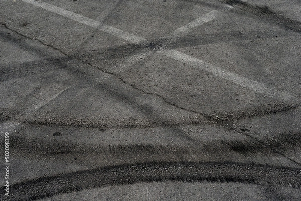 Fototapeta Asphalt texture with white line and tire marks. Smooth asphalt road. Tarmac dark grey grainy road background.Top view