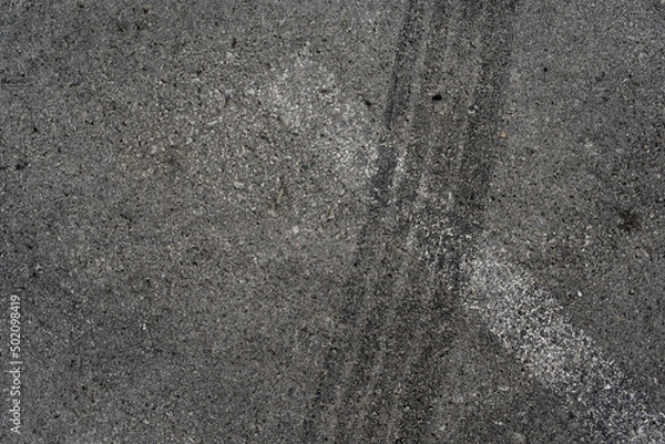 Fototapeta Asphalt texture with white line and tire marks. Smooth asphalt road. Tarmac dark grey grainy road background.Top view