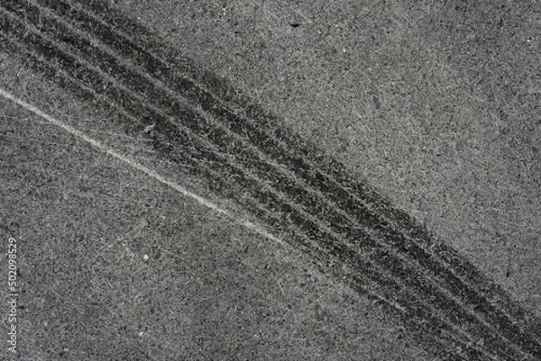 Fototapeta Asphalt texture with white line and tire marks. Smooth asphalt road. Tarmac dark grey grainy road background.Top view