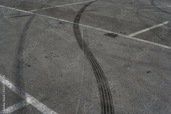 Fototapeta Asphalt texture with white line and tire marks. Smooth asphalt road. Tarmac dark grey grainy road background.Top view