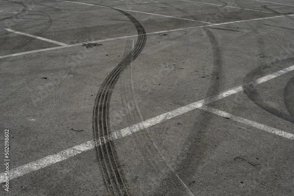 Fototapeta Asphalt texture with white line and tire marks. Smooth asphalt road. Tarmac dark grey grainy road background.Top view