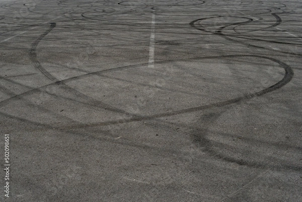 Fototapeta Asphalt texture with white line and tire marks. Smooth asphalt road. Tarmac dark grey grainy road background.Top view