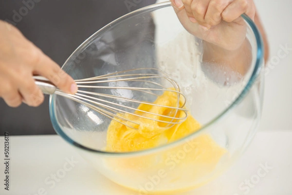 Fototapeta close up of hand whisking eggs