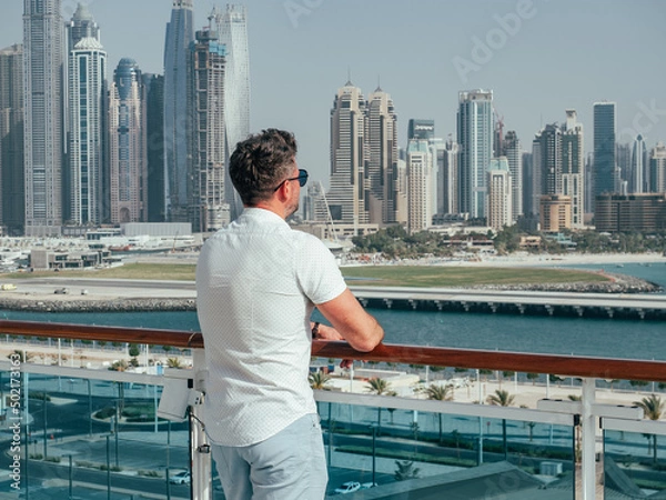 Fototapeta Fashionable man standing on the empty deck of a cruise liner against the backdrop of the setting sun. Closeup, outdoor. Vacation and travel concept
