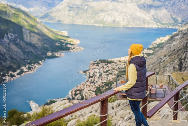 Fototapeta Woman tourist enjoys the view of Kotor. Montenegro. Bay of Kotor, Gulf of Kotor, Boka Kotorska and walled old city. Travel to Montenegro concept. Fortifications of Kotor is on UNESCO World Heritage