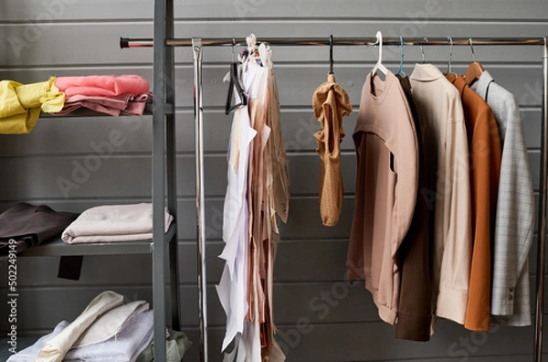 Fototapeta Part of long rack with variety of casual clothes of different colors hanging in modern boutique or workshop of tailor or fashion designer