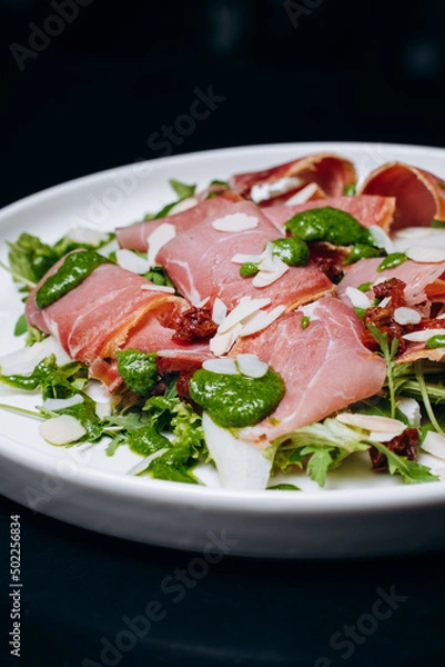 Fototapeta salad with prosciutto and avocado with avocado sauce on a white plate