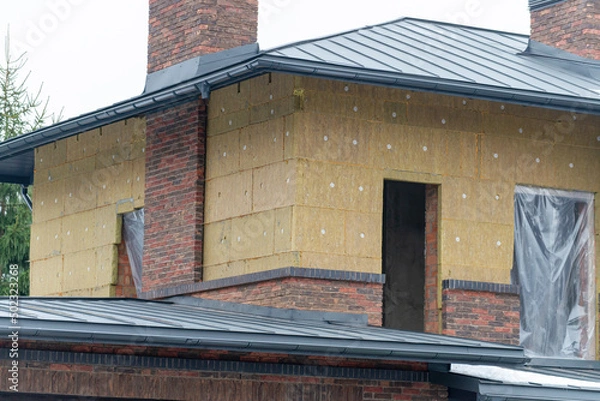 Fototapeta Insulation of brickwork with mineral wool. Thermal insulation of a house wall on a building site
