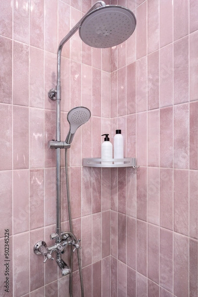 Fototapeta Bottles for shampoo and gel in the bathroom against the backdrop of pink tiles and shower.