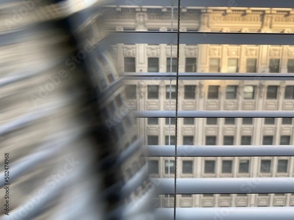 Fototapeta Abstract pattern created with prism in front of camera lens. Facade of a historic building seen through window with partial distortion. Focus on Venetian blinds