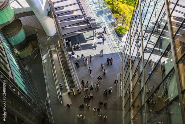 Fototapeta Overhead view of people walking between modern buildings