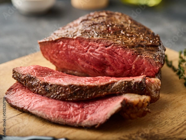 Obraz Barbecue Grilled rump cap or brazilian picanha beef meat steak in a wooden tray. Grey background