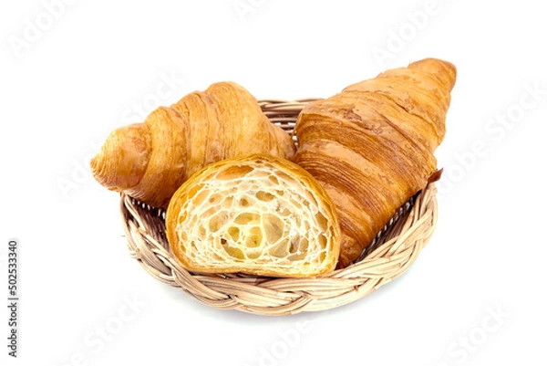Fototapeta Plain Croissants and cut in half, showing the cross section in a wicker basket, a classic crescent-shaped croissant. isolated on a white background.