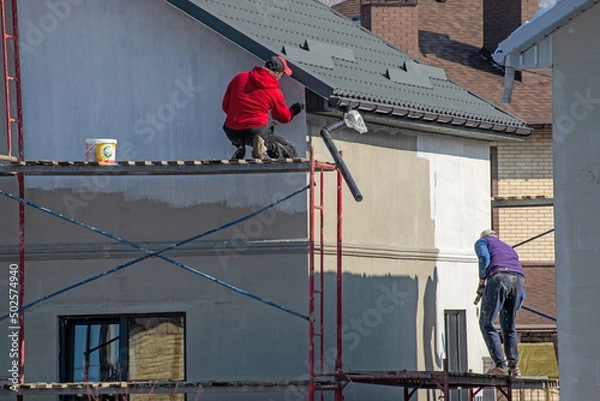 Fototapeta close up details of painting walls, industrial worker using roller and other tools for painting walls of new house
