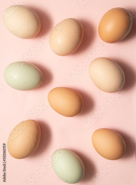 Fototapeta Colorful pattern made of natural organic eggs on pastel light pink background. Creative minimalistic Easter concept.