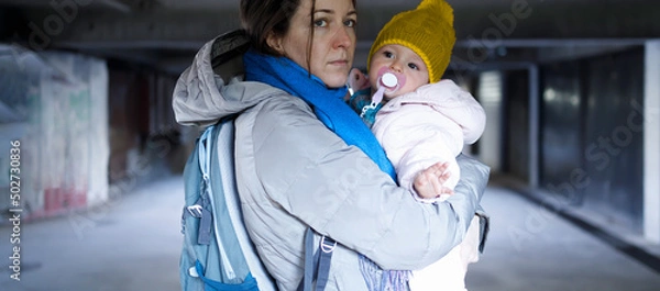 Fototapeta Devoted mother carrying her small child in the bomb shelter