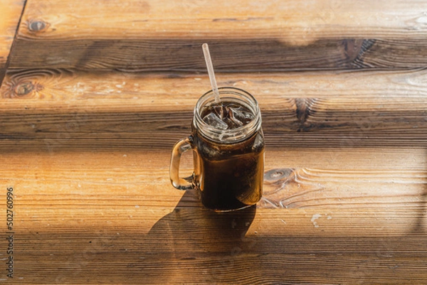 Obraz Ice Americano coffee in a glass on wooden table in morning.