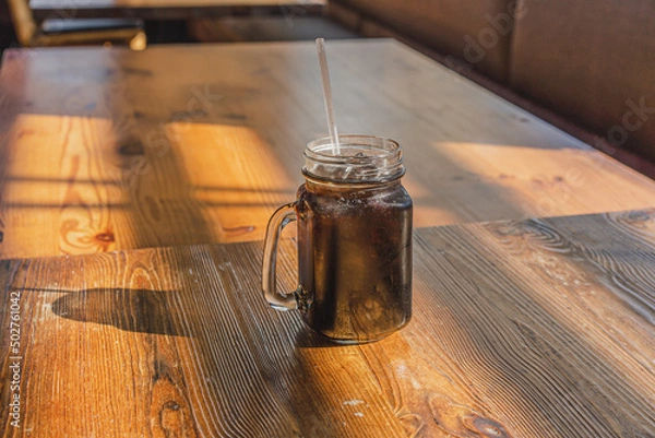 Obraz Ice Americano coffee in a glass on wooden table in morning.